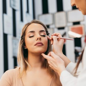 Professional makeup artist doing professional make up of beautiful young woman.